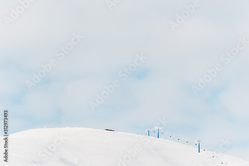 scenic view of snowy mountain with gondola lift and white fluffy clouds in sky
