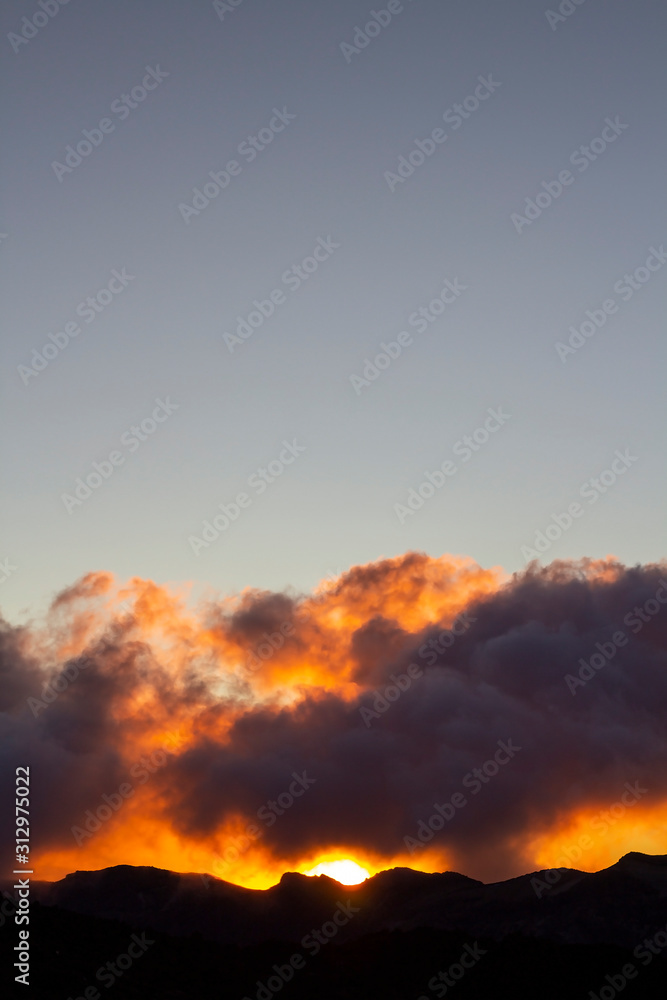 Mountain silhouette with clouds at sunrise time.