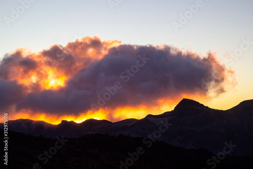 Mountain silhouette with clouds at sunrise time.