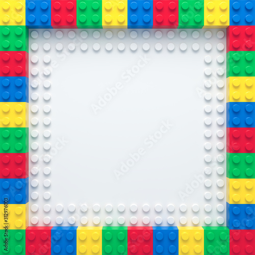 Frame of colorful toy bricks on white construction plate
