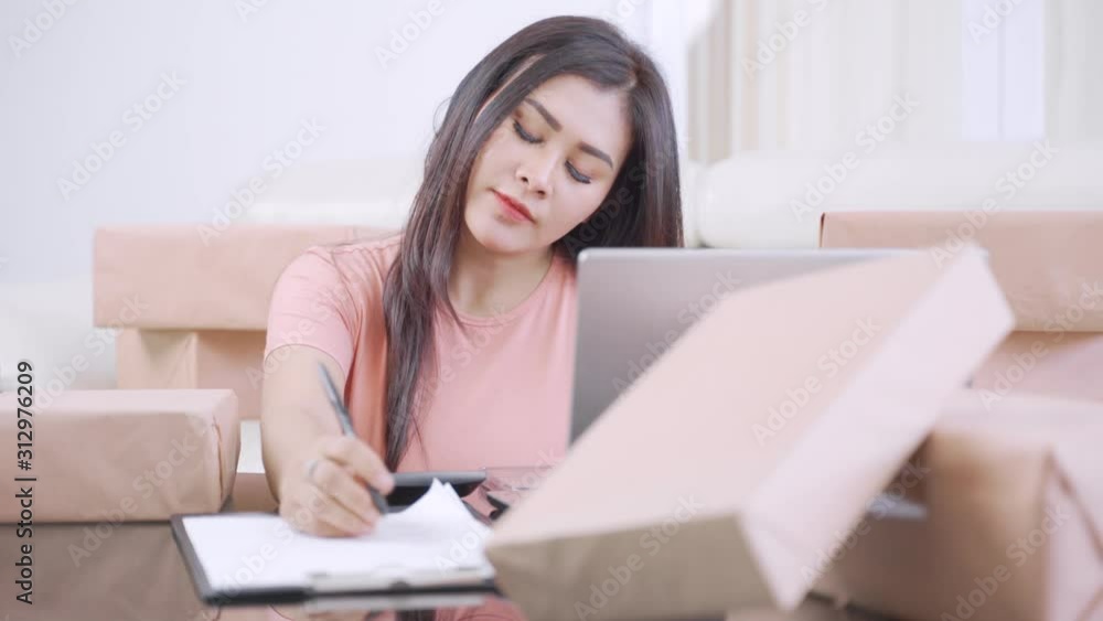Stressed woman working at home with calculator, laptop, and cardboard. Small Medium Enterprise or Start up concept. Shot in 4k resolution Stressed woman working at home with calculator, laptop, and cardboard. Small Medium Enterprise or Start up concept. Shot in 4k resolution