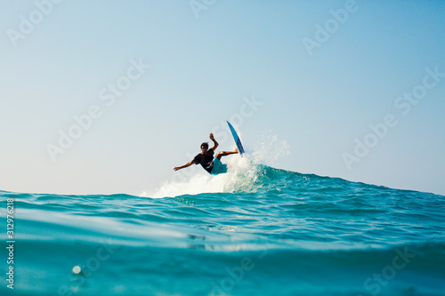 Male surfer riding turquoise blue ocean wave photo
