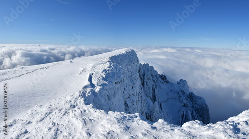 Winter mountains, Panoramic view of mountain peak above the clouds. Snowy landscape wallpaper © Ivan