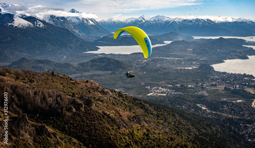 Paragliding over Nahuel Huapi lake and mountains of Bariloche in Argentina, with snowed peaks in the background. Concept of freedom, adventure, flying