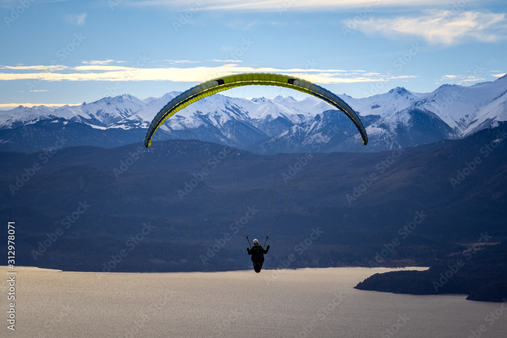 Paragliding over Nahuel Huapi lake and mountains of Bariloche in Argentina, with snowed peaks in the background. Concept of freedom, adventure, flying Paragliding over Nahuel Huapi lake and mountains of Bariloche in Argentina, with snowed peaks in the background. Concept of freedom, adventure, flying