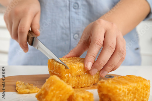 Woman cutting fresh honeycomb at table, closeup