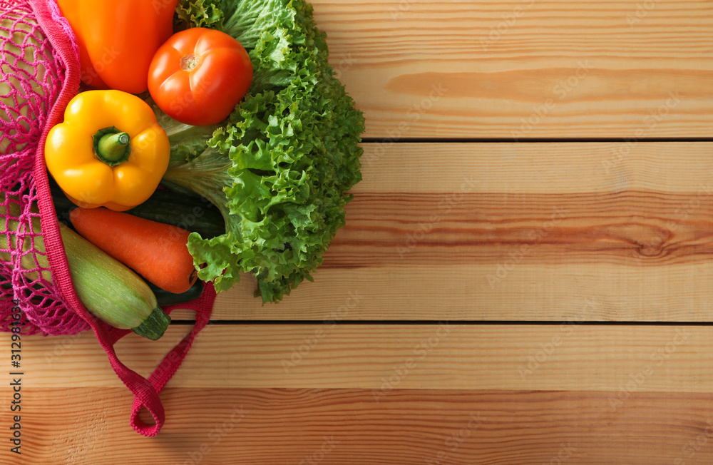 Net bag with vegetables on wooden table, top view. Space for text Net bag with vegetables on wooden table, top view. Space for text