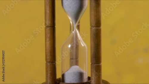 Hourglass with grey sand and yellow backround