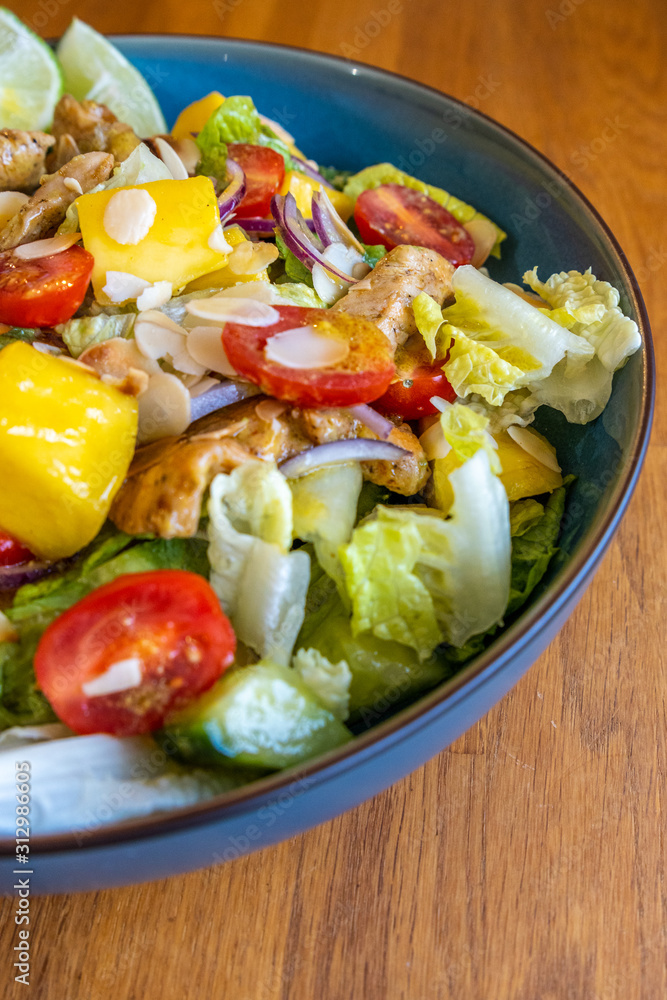 Top view of a homemade chicken salad with mango, tomatoes and fresh onion