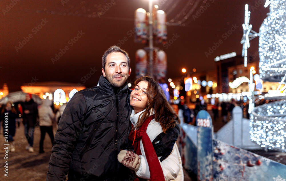 Loving couple walks around the evening Christmas city in winter.