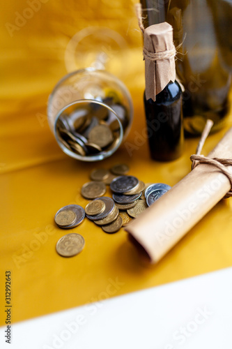 scroll of paper with wine bootle and glass with coins on yellow background photo