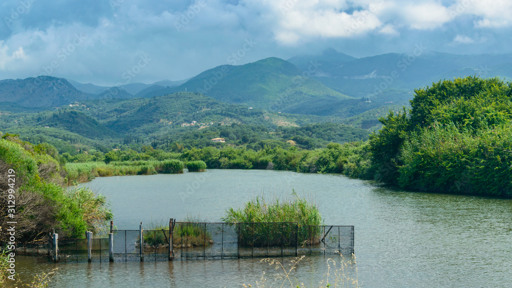 Fototapeta premium A riverbed at the foot of green mountains, a storm is coming to the mountain peaks.