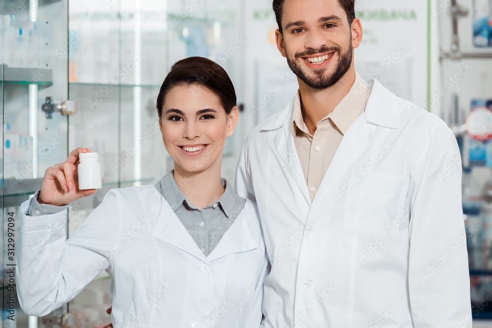 Smiling pharmacists with pills looking at camera in drugstore Smiling pharmacists with pills looking at camera in drugstore