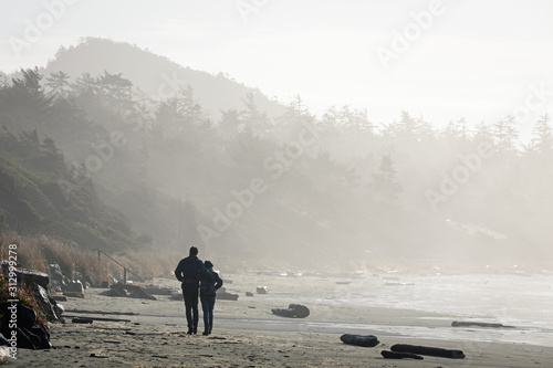 A couple take a romantic walk on a seculded beach with early morning mist