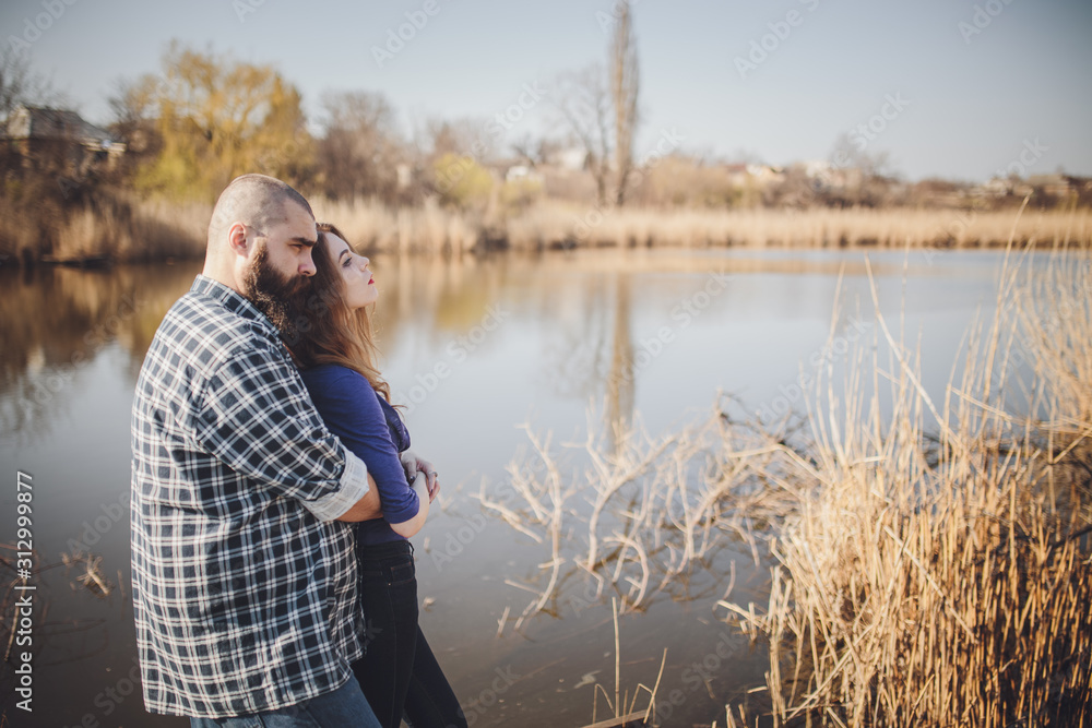 young and stylish couple standing near water in park