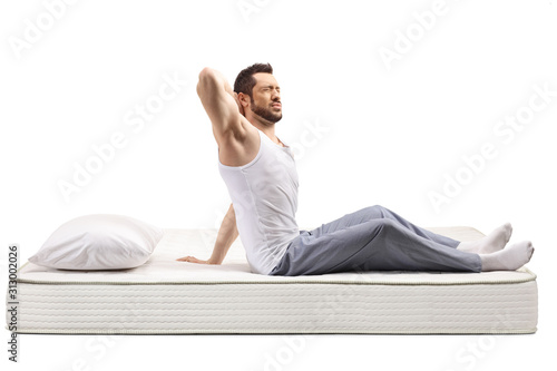 Canvas Print Young man on a bed mattress holding his stiff neck