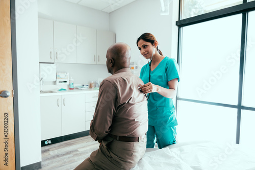 Nurse listening to stethoscope on patient's back