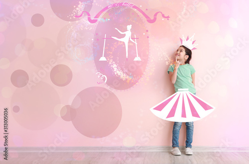Cute little girl dreaming of becoming ballerina while standing near color wall