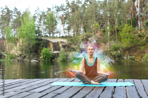 Fotografia Beautiful young woman practicing yoga outdoors near river