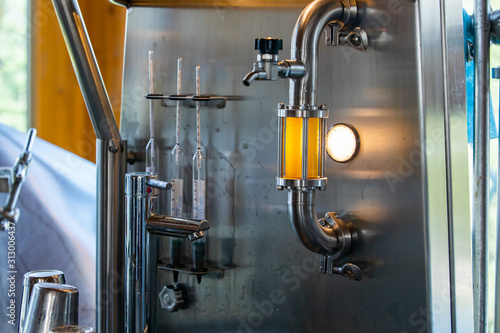 beer quality control equipment, sight glass full of golden beer on stainless steel pipe with light and hose bib faucet valve for taking samples