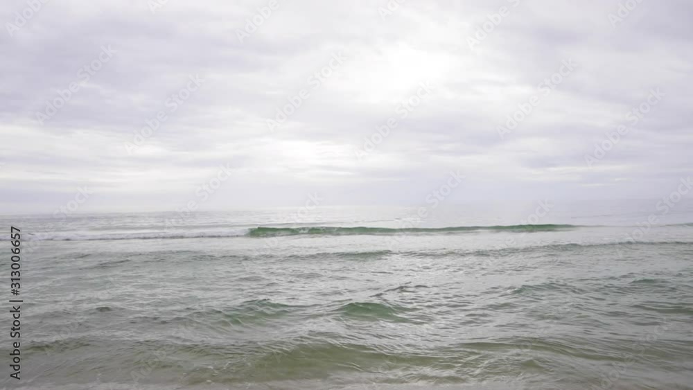 camera pans up from beach ocean waves up to clouds camera pans up from beach ocean waves up to clouds