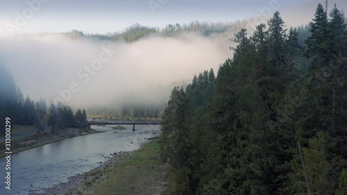 Aerial: Old bridge crossing the Lochsa river in a forest. Morning fog is in the hills. Nez Perce Clearwater National Forests, Idaho, USA. 6 October 2019 photo