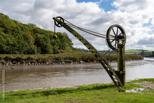 Rusty old metal winch or crane for cargo by the tidal River Tamar at Cotehele in Devon photo