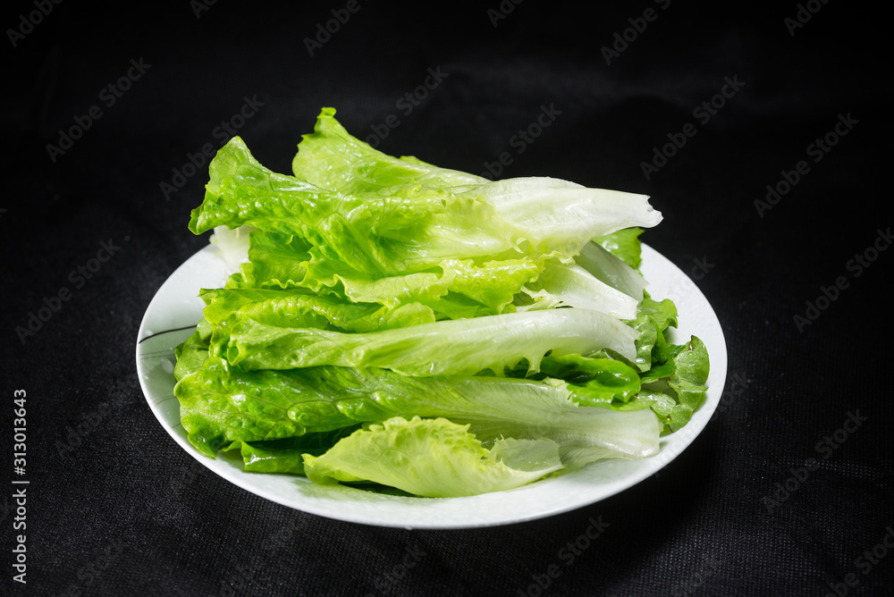 White container of fresh healthy lettuce on black background. White container of fresh healthy lettuce on black background.