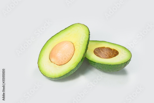 A cut avocado stands alone on a white background