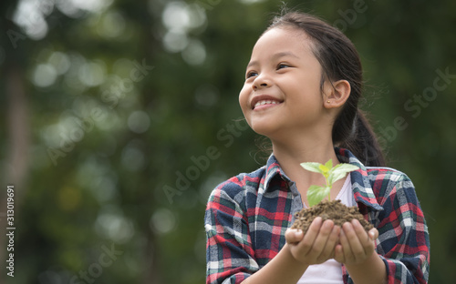 Kid holding young plant in hands against spring green background. environment earth day In the hands of trees growing seedlings. concept ecology