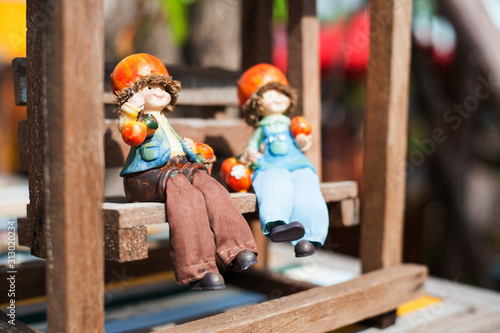 Two dolls sitting on vintage wooden swings