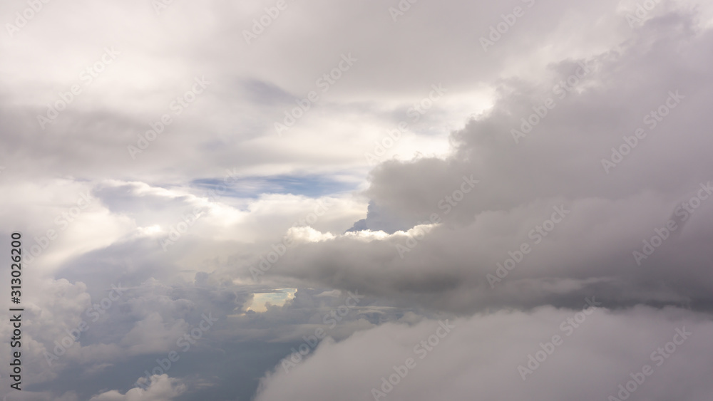 Skyscape view from clear glass window seat of aircraft to cloudscape, traveling on white fluffy clouds and vivid blue sky and sunshine