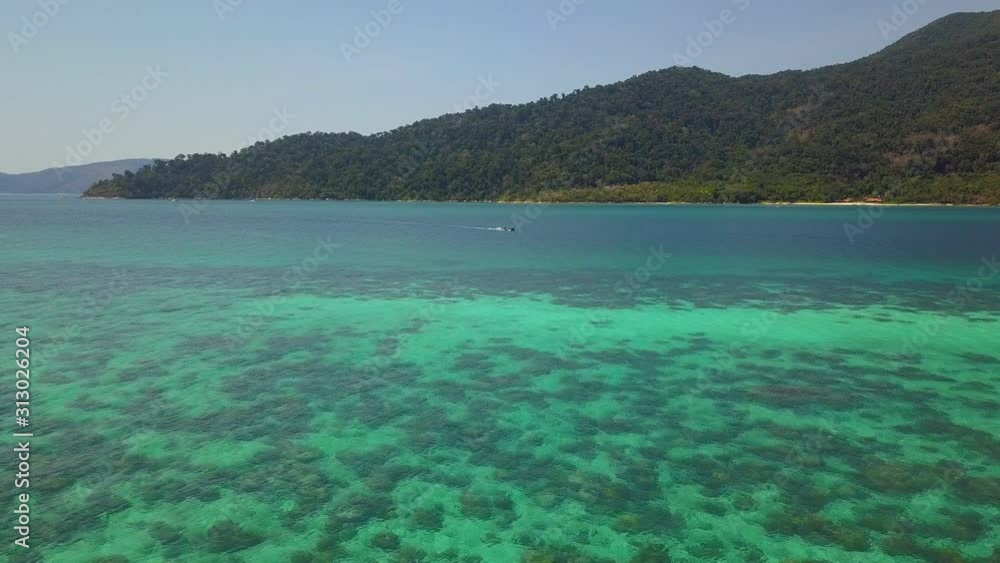 Aerial view of long-tailed boat is sail on the emerald sea. Water traffic with calm andaman sea at Koh Lipe, Satun, Thailand. Dolly motion.
