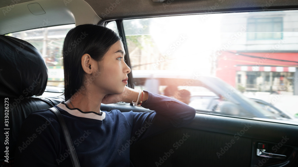 Young Asian woman sitting in a car and looking out the window. Young Asian woman sitting in a car and looking out the window.
