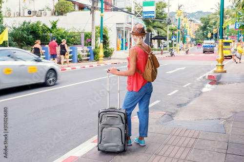  Woman with a travel bag standing on street on vacation. Travel in Asia concept.