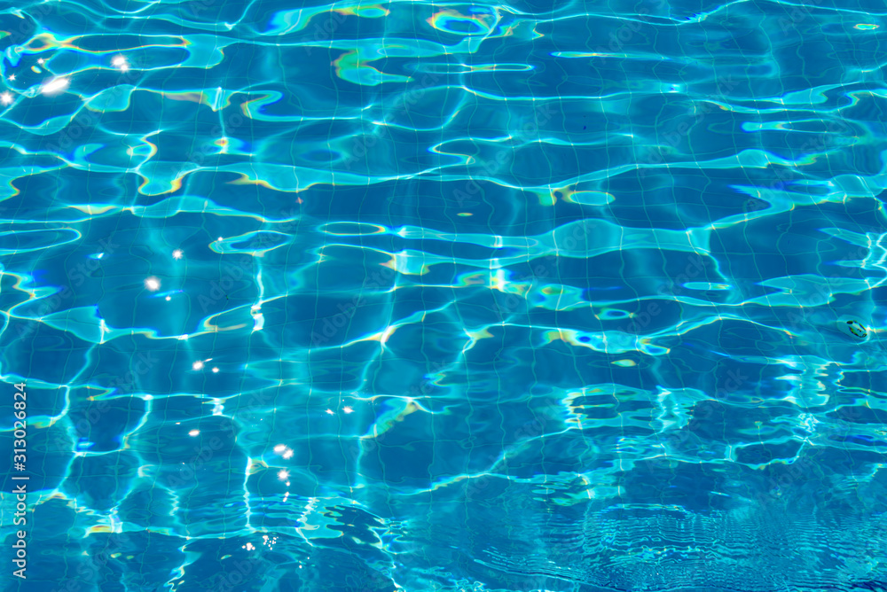 Blue bottom through the transparent water with sunspots of light in the pool