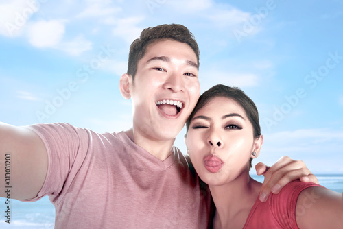 Asian couples making a selfie with a funny face using a camera phone