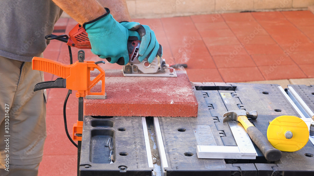 Tile cutter industry equipment. Worker cutting paving tiles for laying on the terrace using circular saw electric