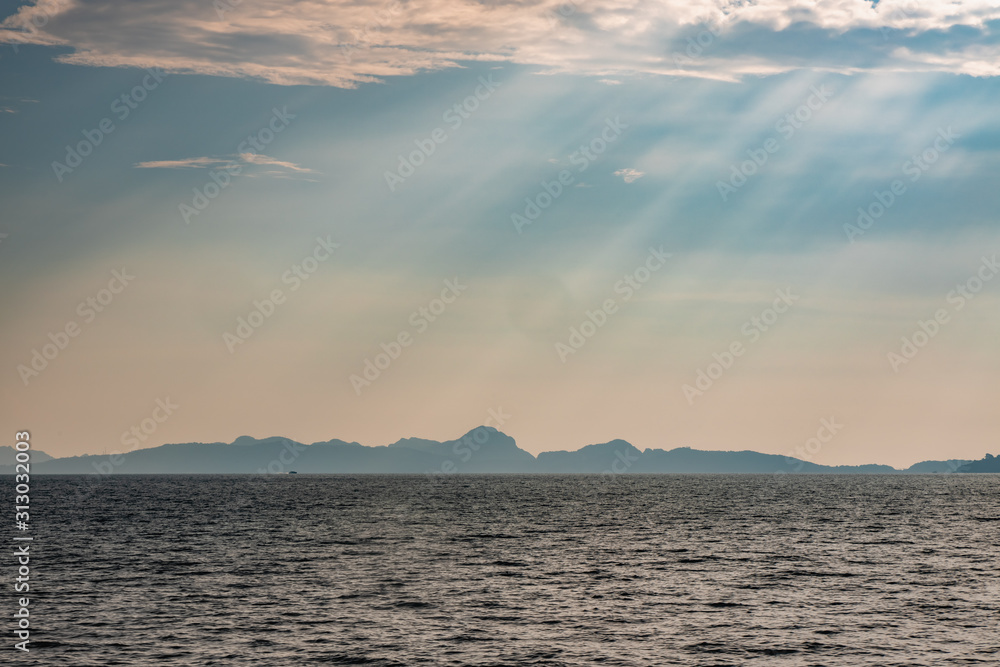 Dramatic sun rays hitting the sea off the coast of Thailand. Hills of Phi Phi Island can be seen in the background.