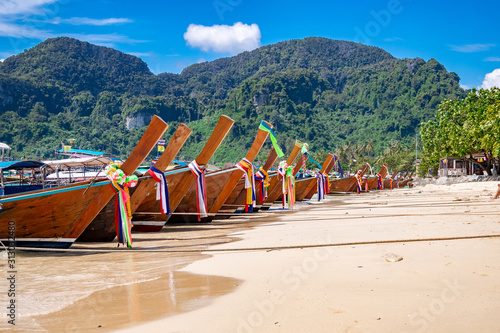 traditional wooden longtail boats parked at a beach in Phi Phi Island. Clear water and clean beach.