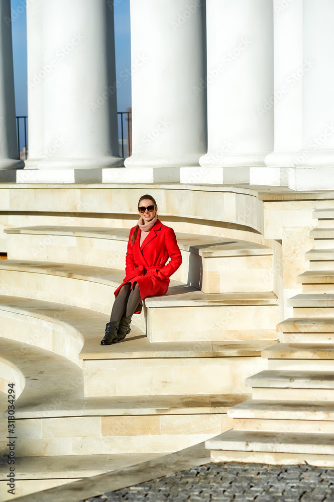 A young woman in a coat on the street of a European city in the cold season