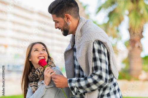 Young woman receives a red rose from a young man