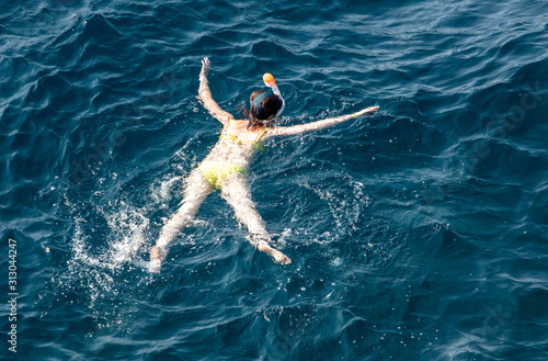 A girl swims in the blue water of the sea