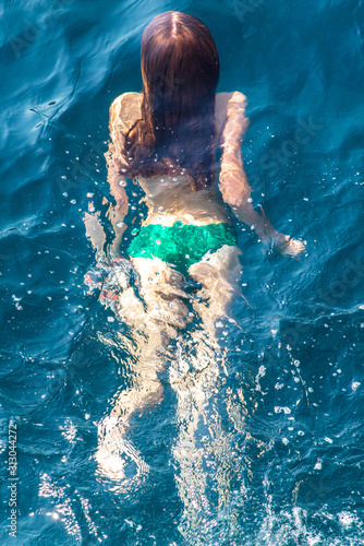 A girl swims in the blue water of the sea © schankz
