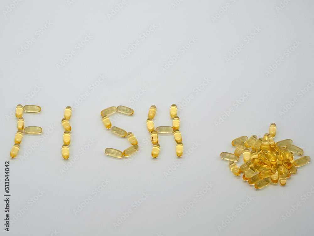 The word FISH is laid out from omega-3 capsules fish oil and a slide of capsules nearby The word FISH is laid out from omega-3 capsules fish oil and a slide of capsules nearby