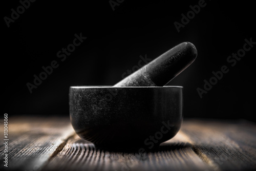 Pestle and mortar with black stone on wooden table