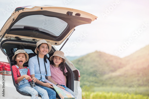 happy woman girl goes to summer travel trip in the car with mountain background. Family and children sitting in a trunk of car look at road map in countryside. travel concept. © nareekarn