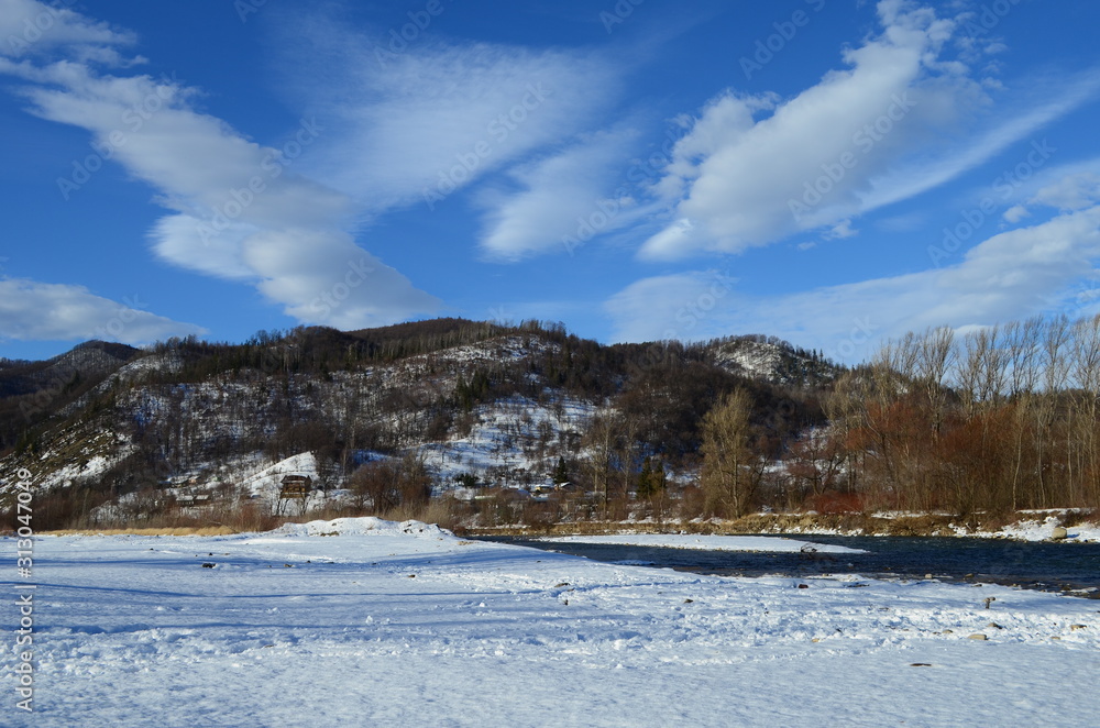 winter landscape in the forest with snow and blue sky and river
