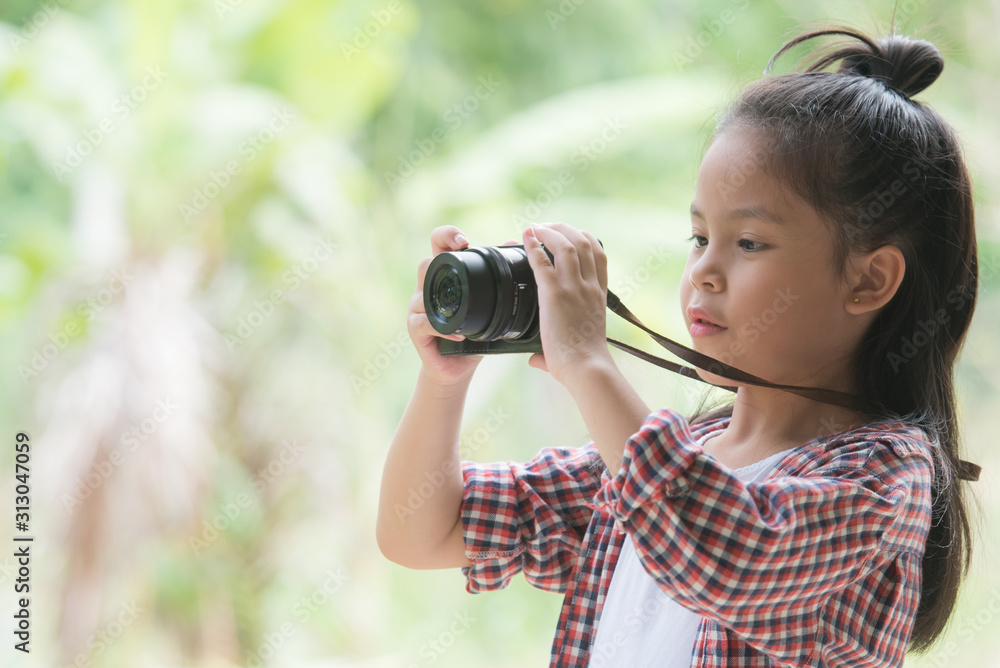 Girl who takes pictures with a photo camera in park on Green natural background. Beautiful smiling child holding a instant camera. Girl who takes pictures with a photo camera in park on Green natural background. Beautiful smiling child holding a instant camera.