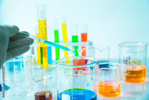 Several test tubes and solution beakers in a science laboratory with liquid of different colors on the laboratory table for chemical background